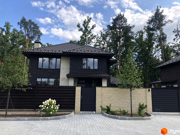 Котеджне містечко Zahrava Village: двоповерховий будинок з темною цегляною облицовкою, великими вікнами та черепичним дахом. Прибудинкова територія з кам'яним парканом та воротами.