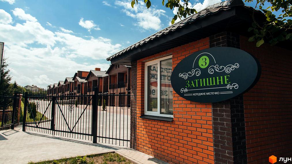 Котеджне містечко Затишне. Фасад будинку з цегли, на тлі якого видно паркан та ряди котеджів.