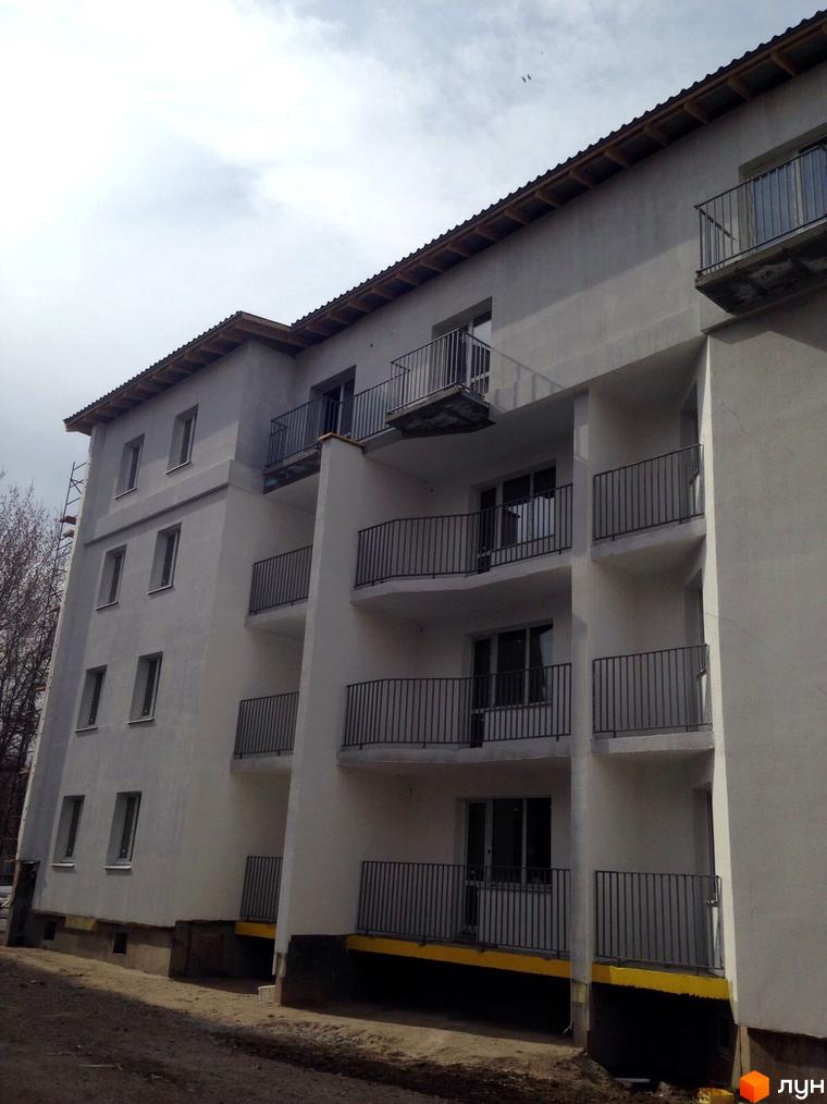 Зовнішній вигляд новобудови ЖК Сузір'я 2019 з балконами та вікнами. Будівельний проєкт з сірим фасадом та жовтою смугою біля основи.