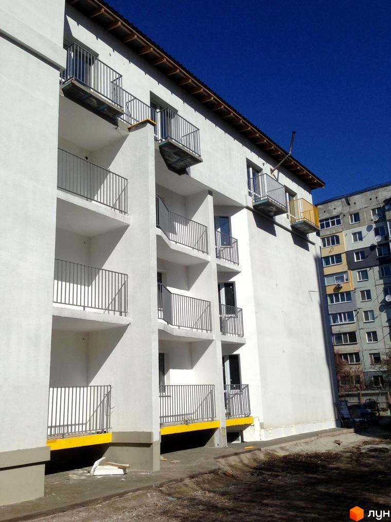 Зовнішній вигляд новобудови ЖК Сузір'я 2019 з балконами та прибудинковою територією. Будівельний проєкт з білими фасадами та сірими огорожами.