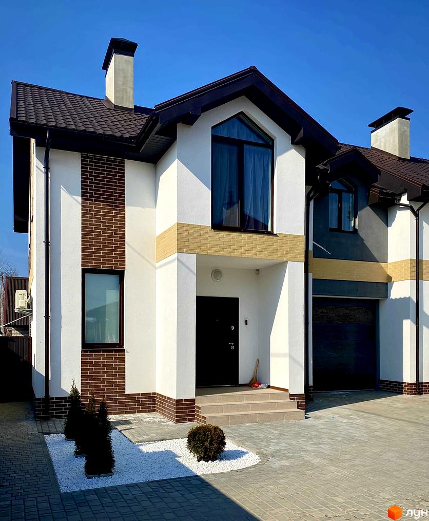 Таунхаус „Соборний“ з білою штукатуркою, коричневою цеглою та великими вікнами. Прибудинкова територія з бруківкою та декоративними рослинами.