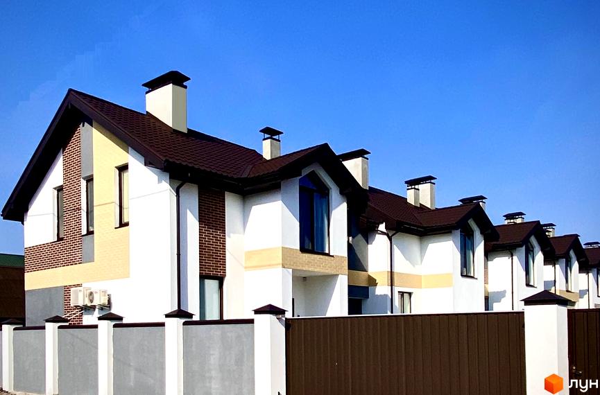 Таунхаус „Соборний“ – сучасний житловий комплекс з білими фасадами, коричневими дахами та цегляними вставками. Перед будинками розташована огорожа та зелені насадження.