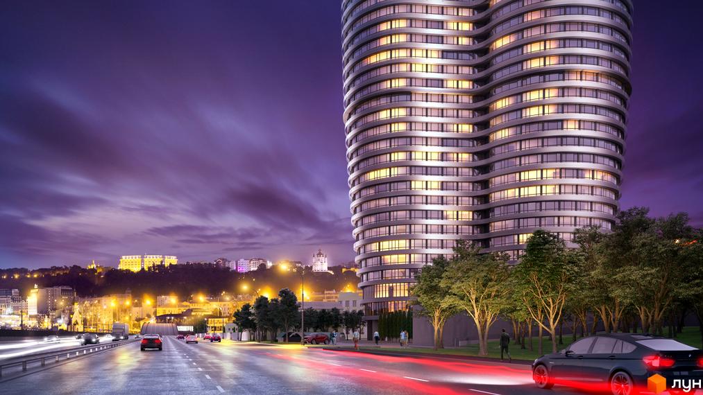 Житловий комплекс OASIS – це вишукана новобудова з хвилястим фасадом та підсвіченими вікнами, що розташована біля дороги з автомобілями та деревами.