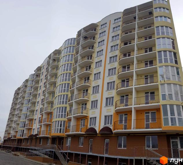 Зображення багатоповерхового будинку в Житловому комплексі Теплий дім. Вигляд фасаду з балконами та великими вікнами.