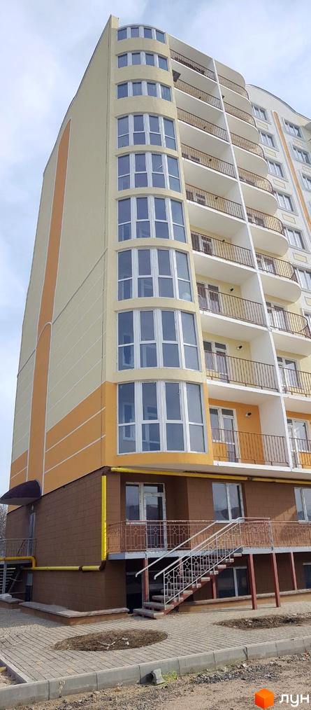 Зображення фасаду багатоповерхового будинку в Житловому комплексі Теплий дім. Вигляд новобудови з великими вікнами та балконами.