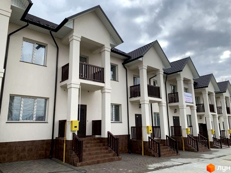 Новобудова на вулиці Обнорського, 10. Зовнішній вигляд будинку з балконами та колонами. Прибудинкова територія з сходами та газовими лічильниками.