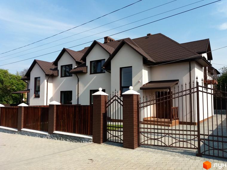 Будинок з коричневим дахом та білими стінами на пров. Красноїльський. Огороджена територія з кованим парканом та цегляними стовпами.