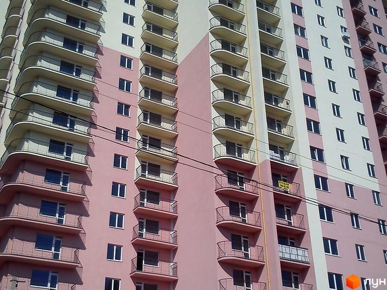 Житловий комплекс Прохорівський з балконами та великими вікнами. Прибудинкова територія з зеленою зоною та паркувальними місцями.