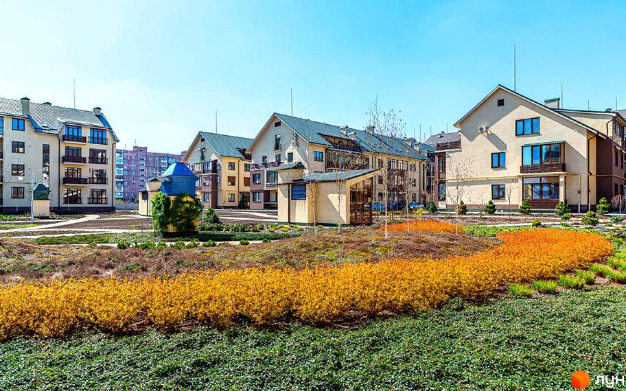 Житловий комплекс Бородино з сучасними будинками та доглянутою прибудинковою територією, оформленою квітами та зеленими насадженнями.
