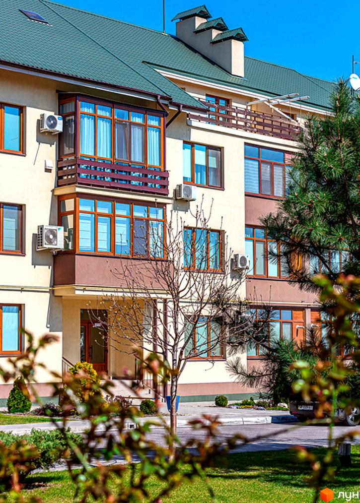 Житловий комплекс Бородино - фасади будівель з коричневими віконними рамами та зеленою черепичною покрівлею. Прибудинкова територія з газоном та деревами.