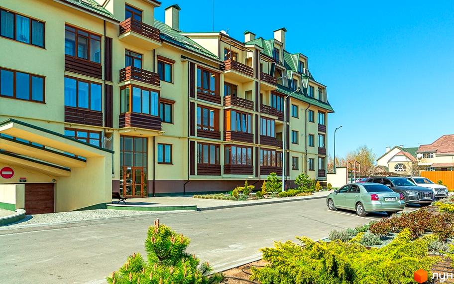 Фасад житлового комплексу Бородино з балконами та вікнами. Прибудинкова територія з парковкою та зеленими насадженнями.