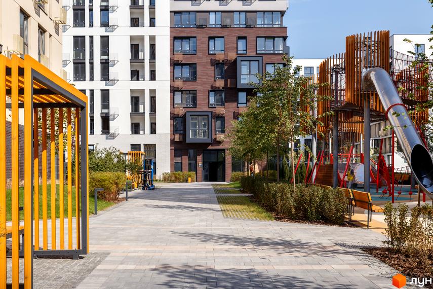 Зовнішній вигляд будинку в Житловому комплексі Файна Таун. На фото прибудинкова територія з ландшафтним дизайном та дитячим майданчиком.