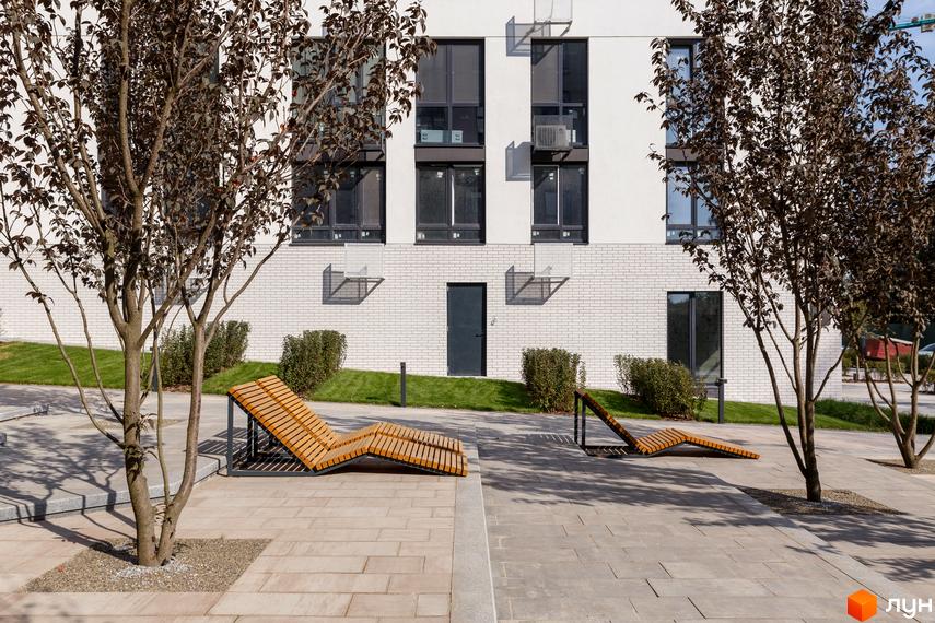 Зовнішній вигляд будинку в Житловому комплексі Файна Таун з лавками для відпочинку на прибудинковій території.