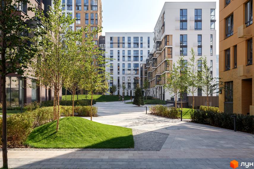 Вигляд на двір з ландшафтним дизайном в Житловому комплексі Файна Таун. Багатоповерхові будинки з великими вікнами.