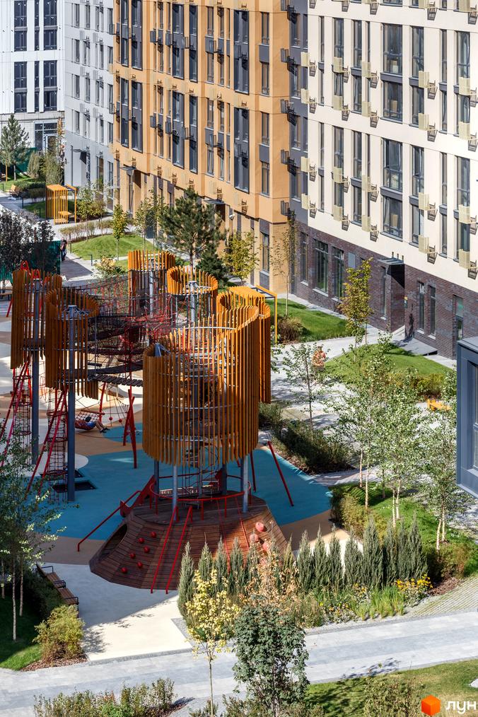 Багатоповерхові будинки Житлового комплексу Файна Таун з світлими та жовтими фасадами. На прибудинковій території великий дитячий майданчик, зелені зони та доріжки.