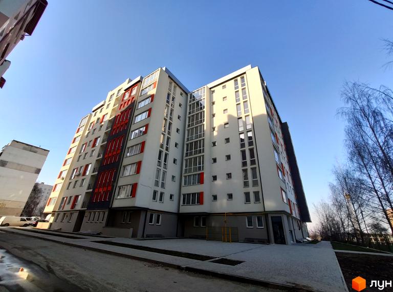 Зовнішній вигляд багатоповерхового будинку на вулиці Руська, 235. На передньому плані — тротуарна плитка та дорога.