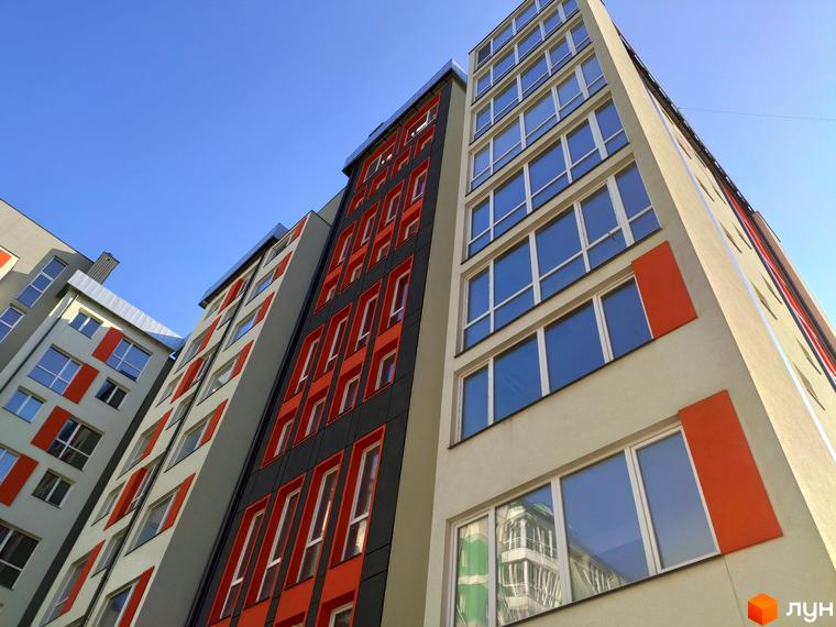 Зовнішній вигляд багатоповерхового будинку на вулиці Руській, 235. Фасад з великими вікнами та яскравими вставками.