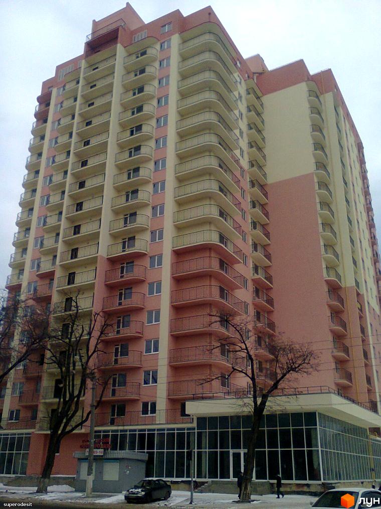 Житловий комплекс Прохорівський з балконами та великими вікнами. Прибудинкова територія з деревами та паркуванням.