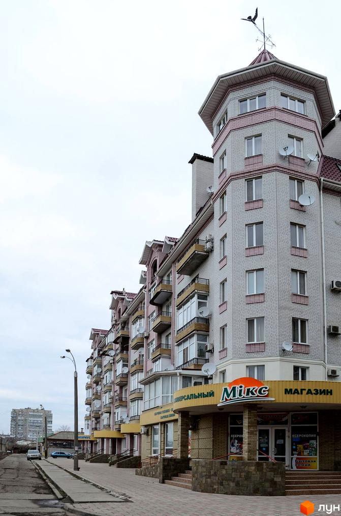 Фасад багатоповерхового будинку з балконами та магазином на першому поверсі, розташованого на вулиці Грецькій, 47.