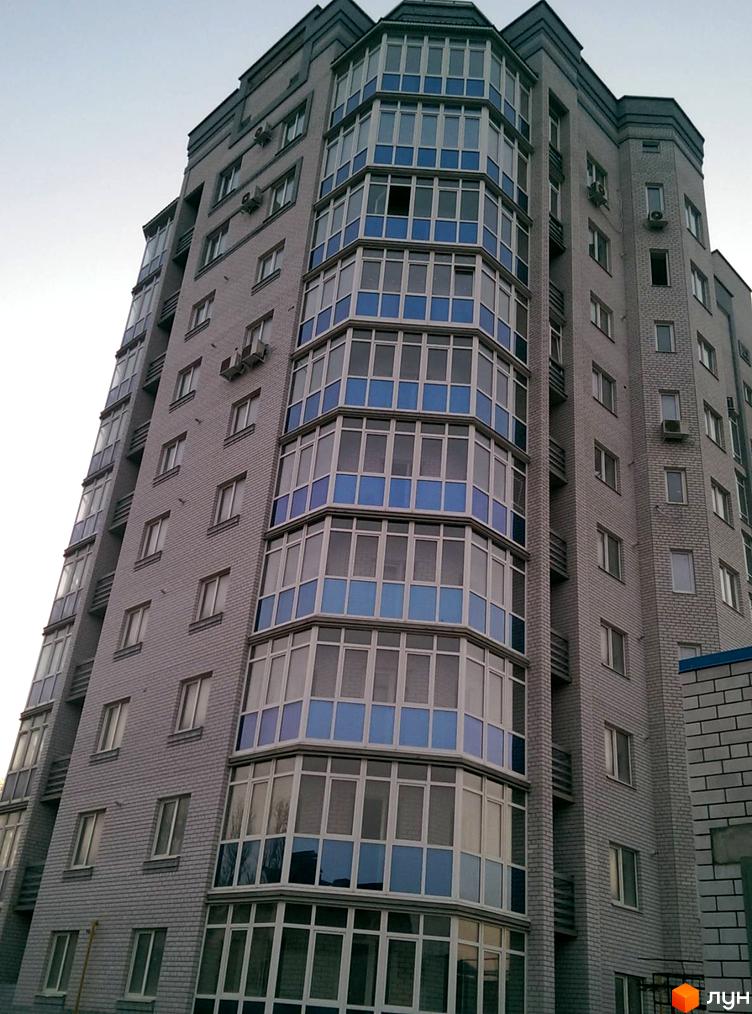 Зовнішній вигляд житлового комплексу на вул. Гостинна, 77, з багатоповерховою будівлею та балконами. Опис фасаду новобудови.