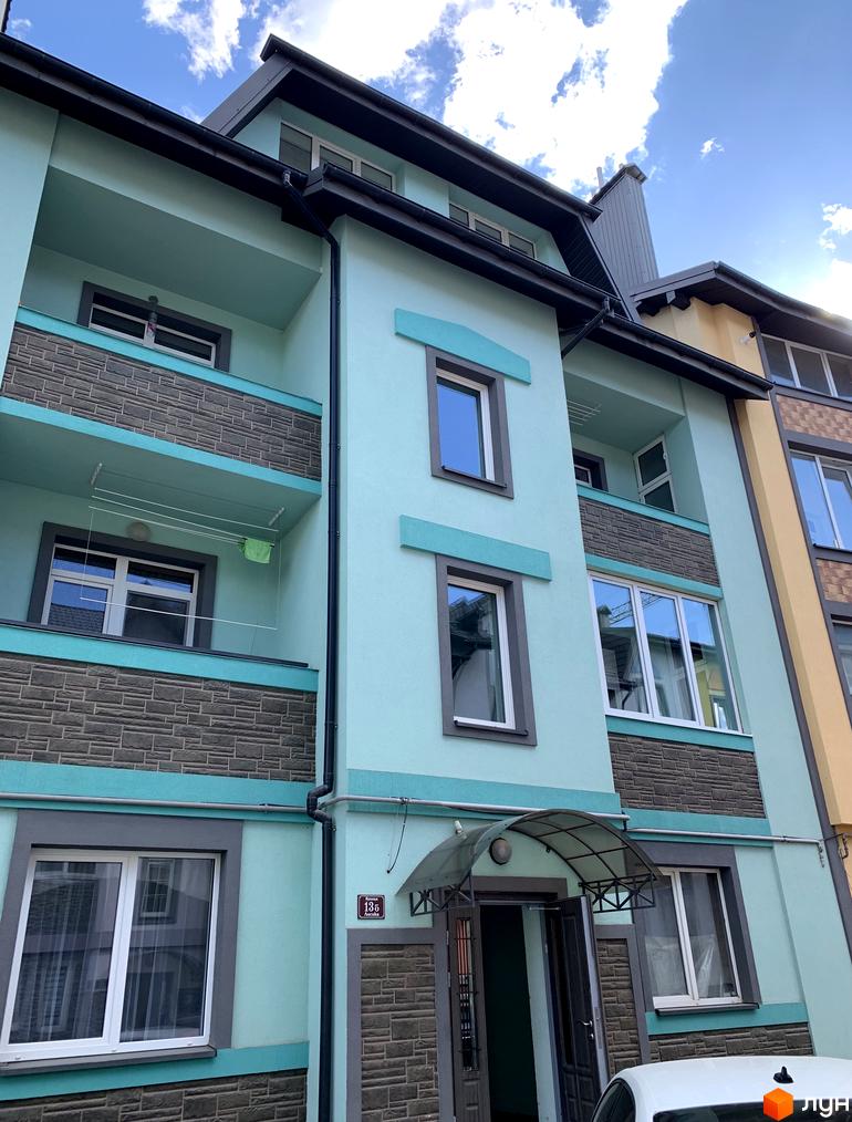 Фасад житлового комплексу Мала Швейцарія у блакитних та сірих тонах з елементами кам'яної кладки. Балкони з навісами та сучасними вікнами.