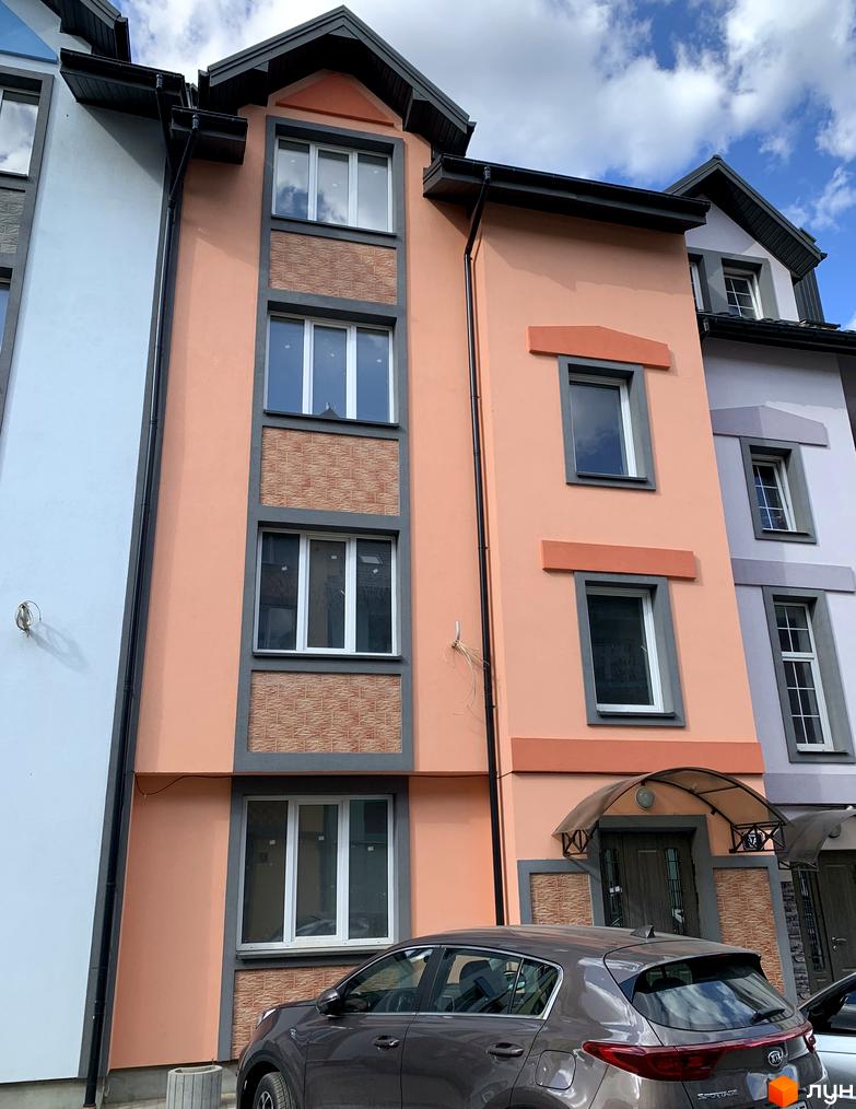 Зовнішній вигляд новобудови ЖК Мала Швейцарія з фасадом персикового кольору та сірими елементами. Поруч припаркований автомобіль.