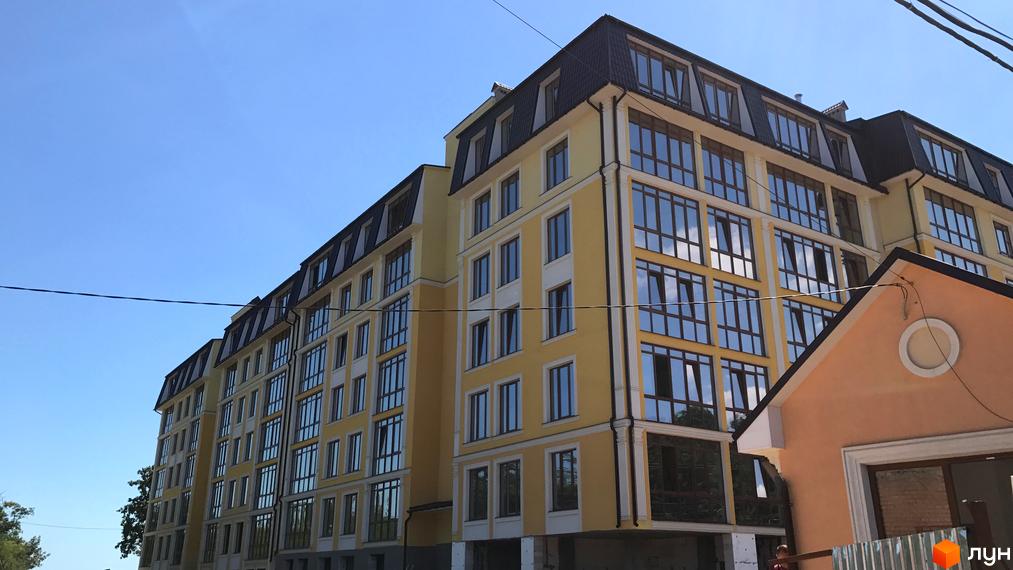 Житловий комплекс Club Marine. Фасад жовтого кольору з білими елементами, великими вікнами та темним дахом. Будинок розташований під блакитним небом.