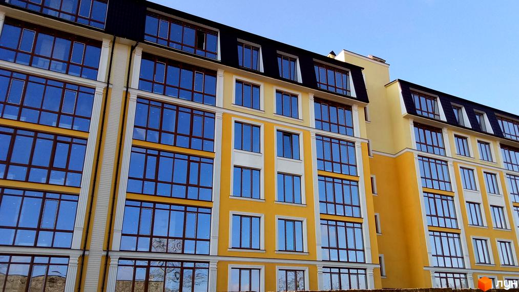 Фасад новобудови ЖК Club Marine з жовтими та білими елементами, великими вікнами та темним дахом. Будинок має багатоповерхову структуру з чіткими лініями та сучасним дизайном.