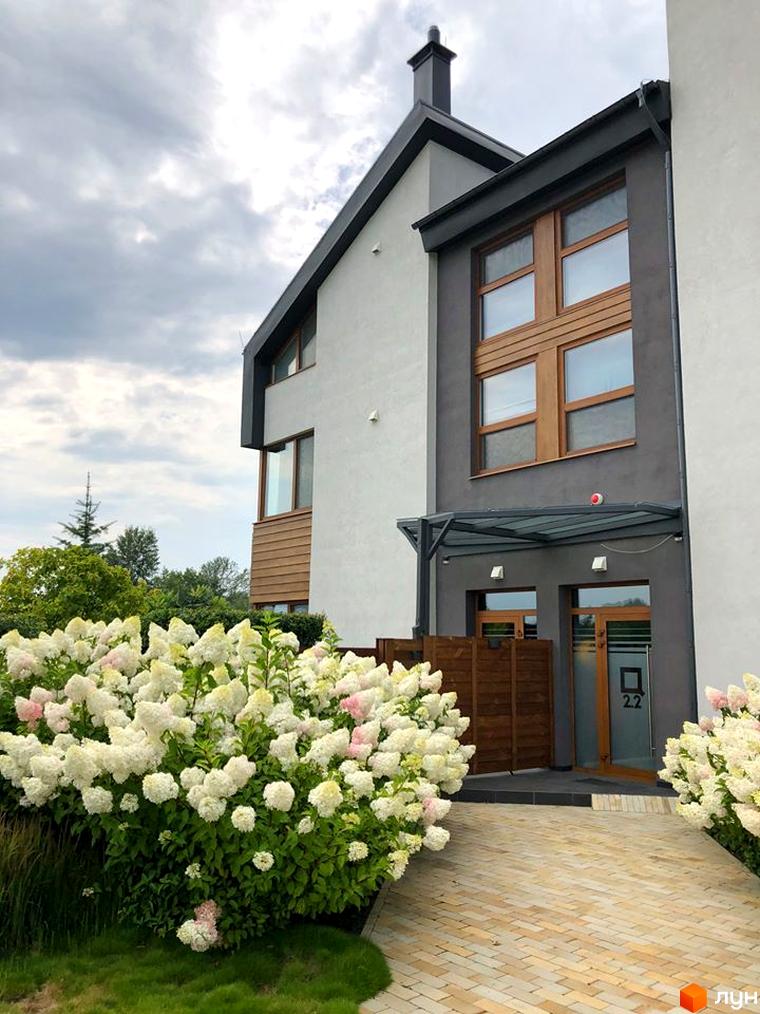 Зовнішній вигляд будинку QDRO - таунхаус. Білі квіти гортензії прикрашають прибудинкову територію.