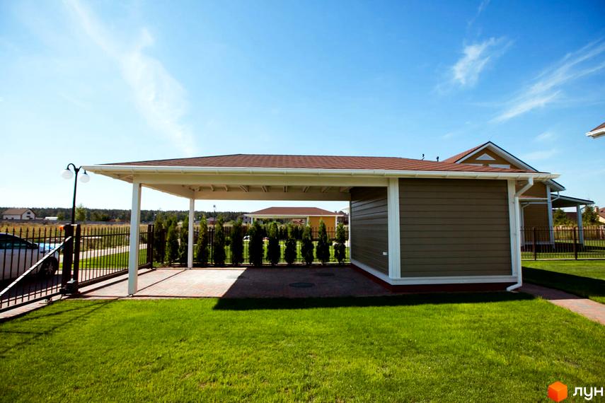 Зовнішній вигляд будинку з коричневим дахом та терасою. На передньому плані доглянутий газон та котеджне містечко КМ Бобриця-Парк.