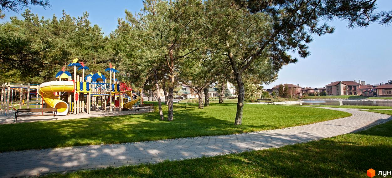Прибудинкова територія житлового комплексу КМ Сонячна долина з дитячим майданчиком та зеленими насадженнями.