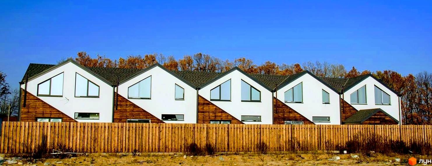 Зовнішній вигляд таунхаусів в Житловому комплексі „Кримський квартал“ з великими вікнами та дерев'яним парканом на передньому плані.