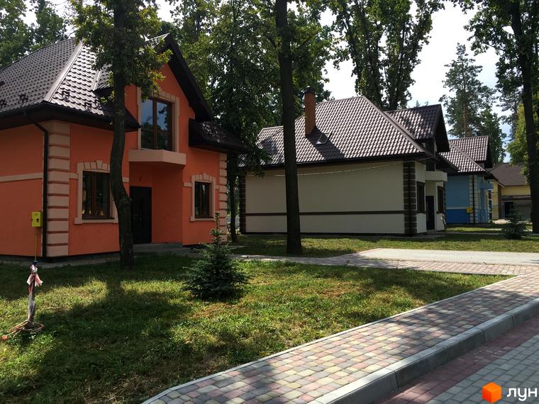 Котеджне містечко Козак хутір: двоповерхові будинки з коричневим дахом та оранжевим фасадом, зелена прибудинкова територія з доріжками з плитки.