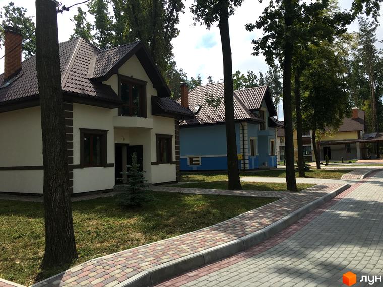 Котеджне містечко Козак хутір: двоповерхові будинки з коричневими дахами та світлими фасадами. Прибудинкова територія з бруківкою та зеленими насадженнями.
