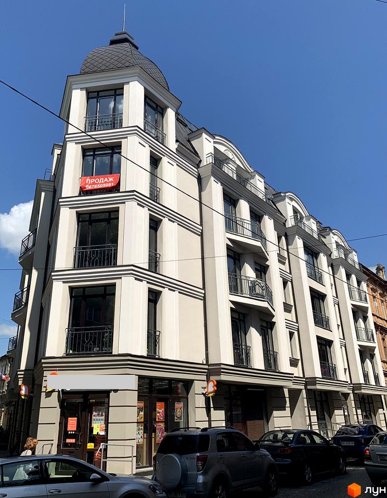 Апарт-комплекс Чайковського, 31 – це багаторівнева будівля зі світлим фасадом, еркерними вікнами та балконами. Перед будинком розташовані автомобілі.