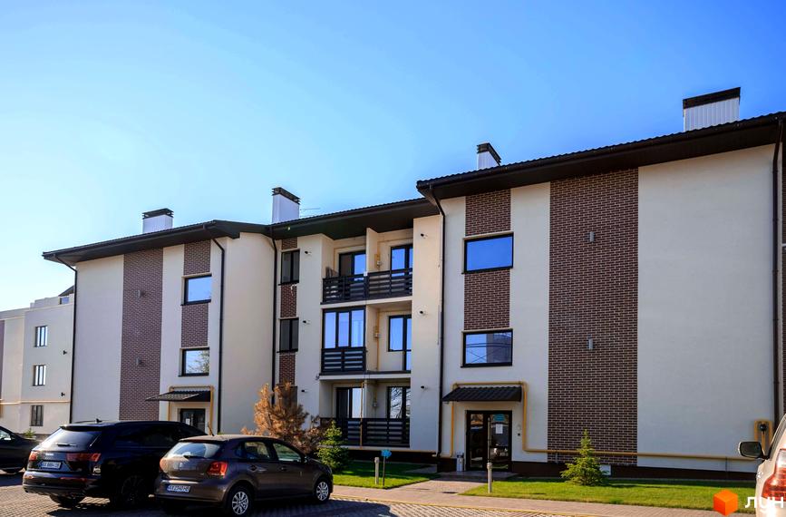 Житловий комплекс Клеменова Дача: багатоквартирний будинок з бежевим фасадом, цегляними вставками, балконами та парковкою.