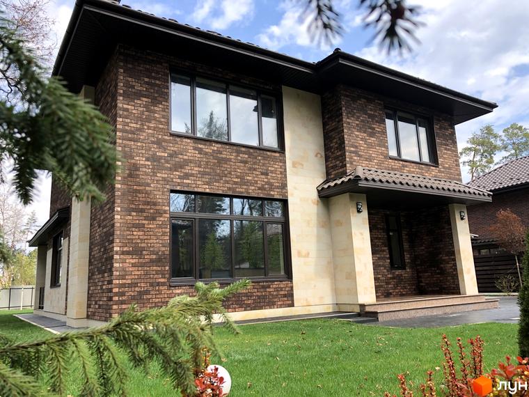 Будинок з коричневої цегли та світлого каменю в Котеджному містечку Zahrava Village, зелена прибудинкова територія.