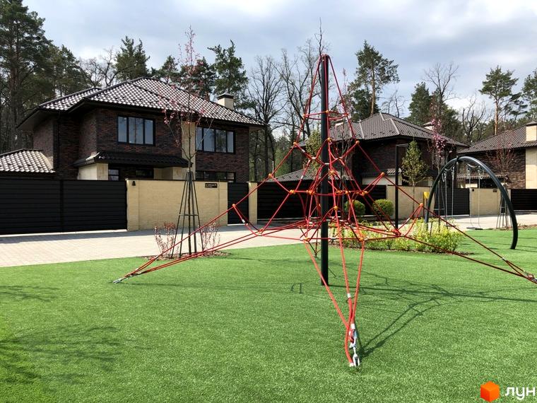 Котеджне містечко KМ Zahrava Village. Сучасні будинки з цегли та зелений газон з дитячим майданчиком.