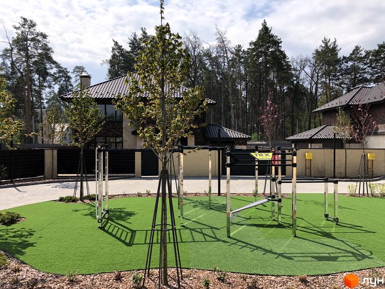 Котеджне містечко КМ Zahrava Village. Зелена зона з тренажерами на території житлового комплексу. Сучасні будинки з цегляною кладкою та темним дахом.
