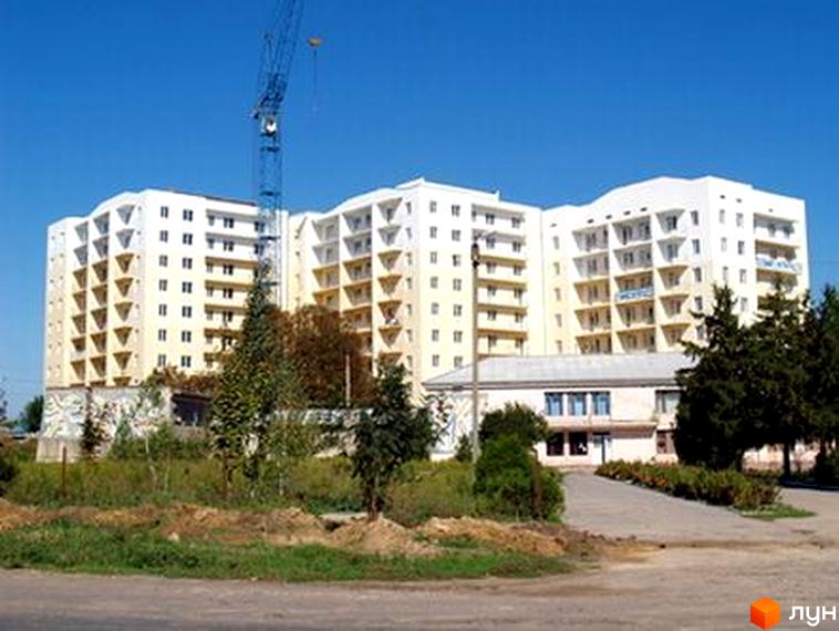 Житловий комплекс Фонтанка сіті: багатосекційна будівля з білими та світло-жовтими фасадами, балконами трикутної форми. Поруч будівельний кран та зелена територія.