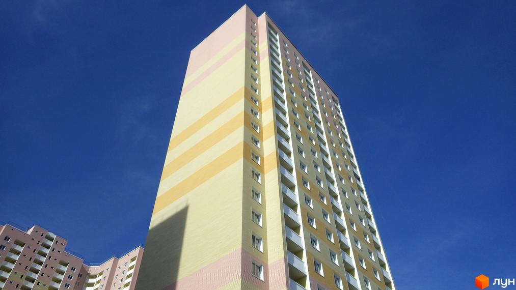 Висотний будинок житлового комплексу Милославичі з кольоровим фасадом. На передньому плані видно прибудинкову територію.