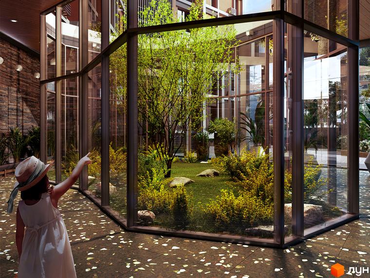 Дитина в капелюсі вказує на зелений внутрішній двір житлового комплексу Echo Park 2. Навколо скляної огорожі багато зелені та каменів.