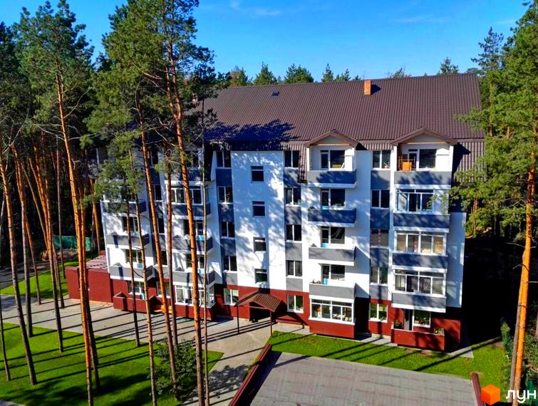 Житловий комплекс Ідея: багатоповерховий будинок з білим та сірим фасадом, коричневим дахом. Оточений високими соснами та зеленими газонами.