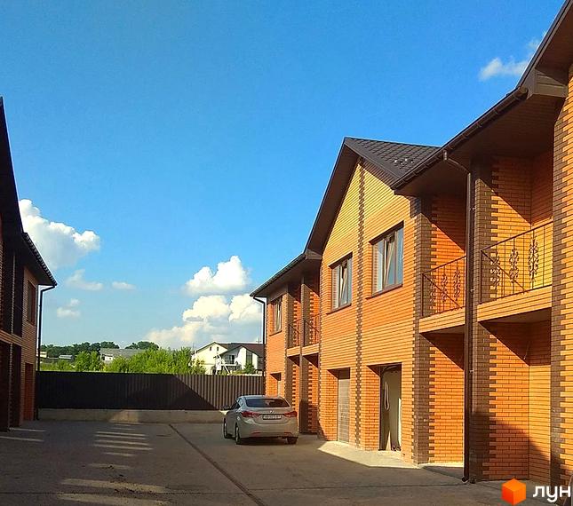 Зовнішній вигляд таунхаусів з цегли з балконами. На території Житлового комплексу „Екологічний“ (Гоголя) припаркований автомобіль.