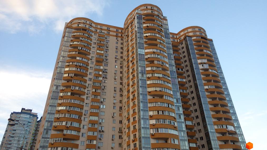 Багатоповерховий житловий комплекс Барвінок з вигнутим фасадом, світлими стінами та помаранчевими балконами.