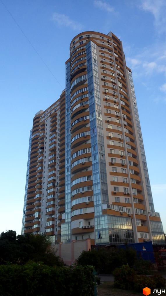 Вид на житловий комплекс Барвінок, висотна будівля з балконами та великими вікнами, зелені насадження на прибудинковій території.