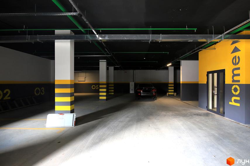 Підземний паркінг Будівельного проєкту „InCo Home на Подолі“. Фотографія паркінгу з автомобілем та дверима.
