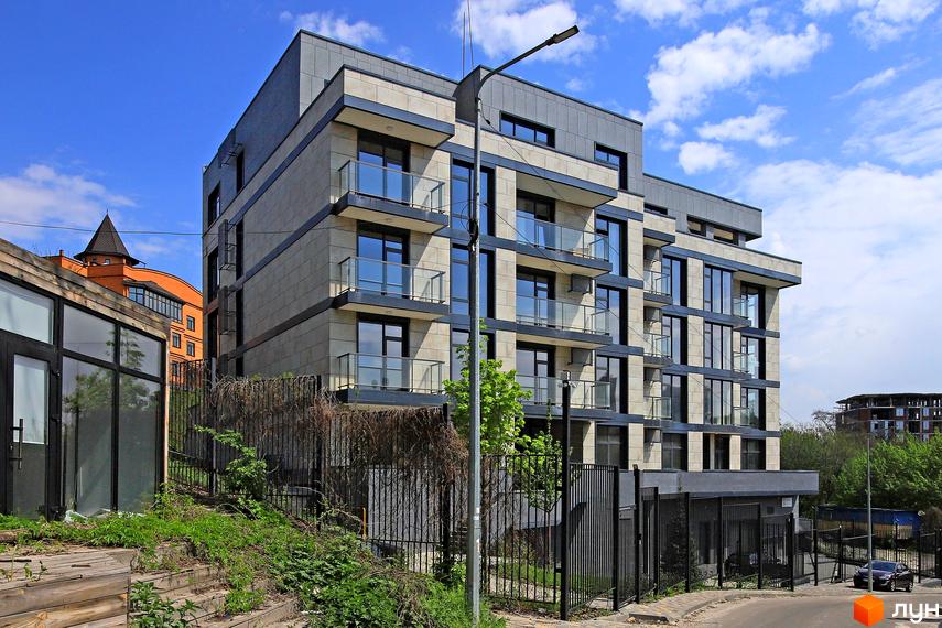 Зображення фасаду Клубного будинку „InCo Home на Подолі“ з великими вікнами та балконами. Навколо будинку видно зелені насадження та огорожу.