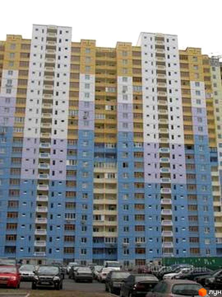 Житловий комплекс на вул. Костянтина Данькевича з кольоровим фасадом та прибудинковою територією з автомобілями.