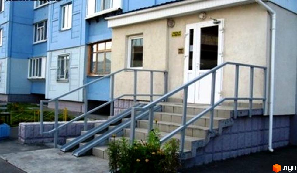 Зовнішній вигляд будинку на вул. Костянтина Данькевича з входом та сходами. Прибудинкова територія з зеленими насадженнями.